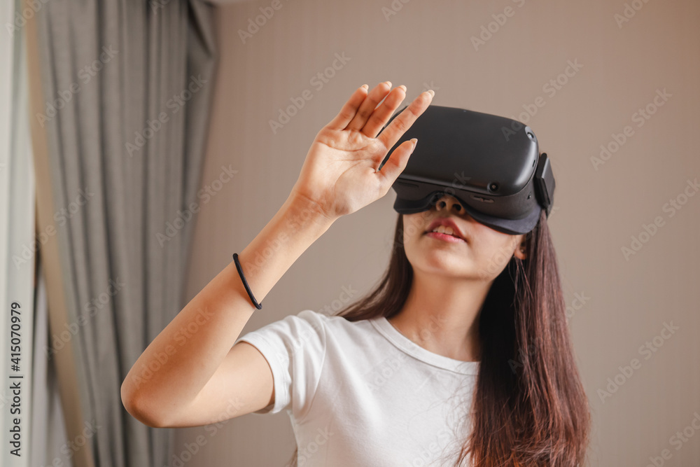 Pretty asian young woman touching air, wearing VR headset or visual reality goggles, glasses or gadget. Girl play videogame of simulator future,futuristic while wearable. Technology of modern concept.