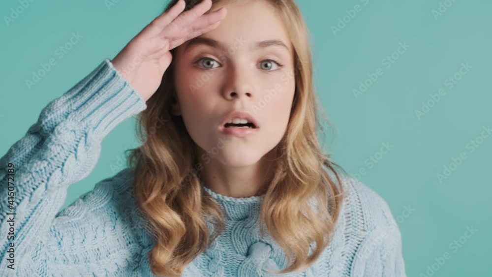 Close up blond teenager girl looking for someone isolated on blue background. Try to find expression