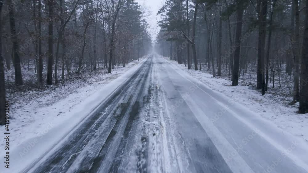 Snowy Road In Between Snow-Covered Forest In A Cold Winter Day - moving shot Snowy Road In Between Snow-Covered Forest In A Cold Winter Day - moving shot