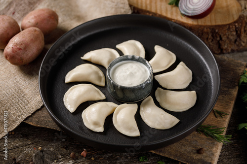 Appetizing traditional Russian dumplings, hand-made with potatoes. Still life on a wooden board. Close-up. photo