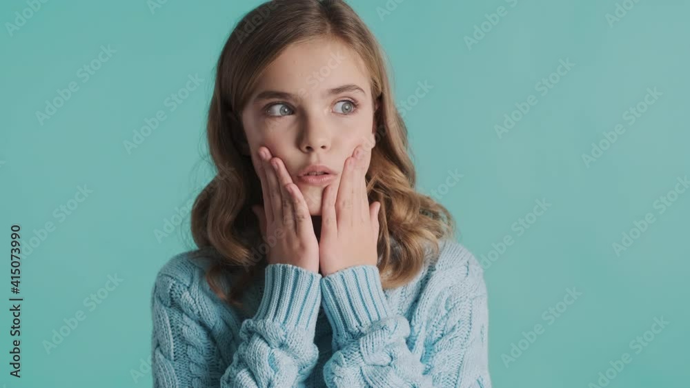 Amazed blond teenager girl dressed in sweater looking scared isolated on blue background. What to do expression Amazed blond teenager girl dressed in sweater looking scared isolated on blue background. What to do expression