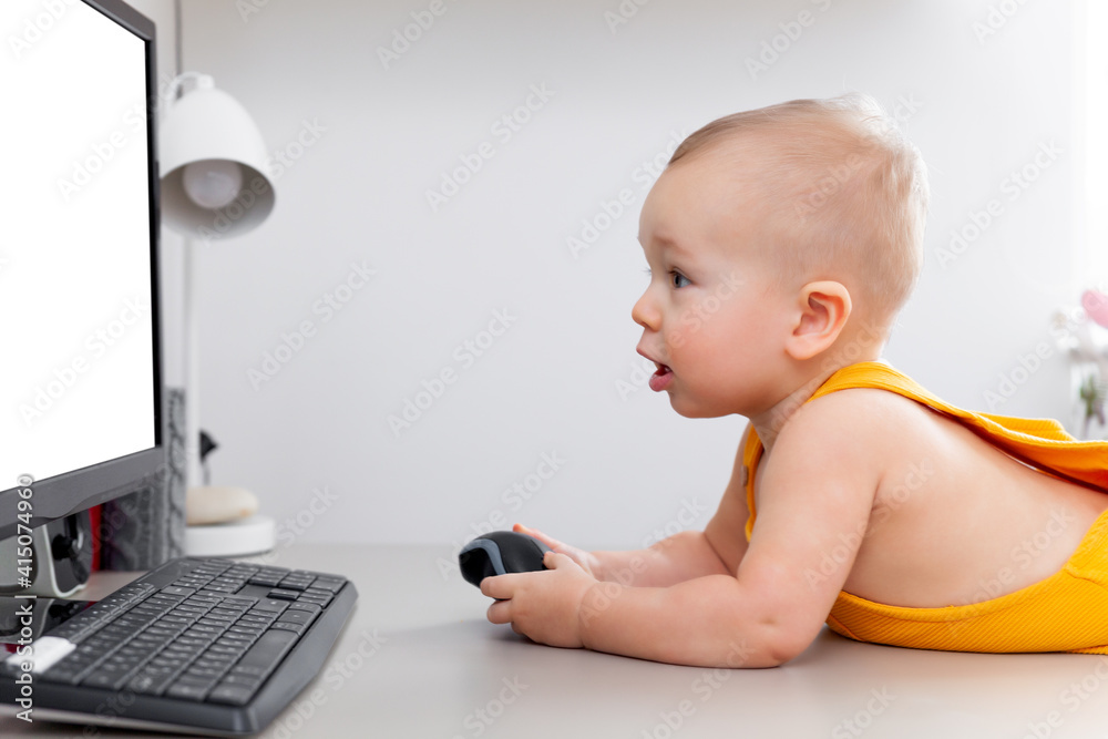 Caucasian funny little baby boy exploring computer, monitor and keyboard Caucasian funny little baby boy exploring computer, monitor and keyboard