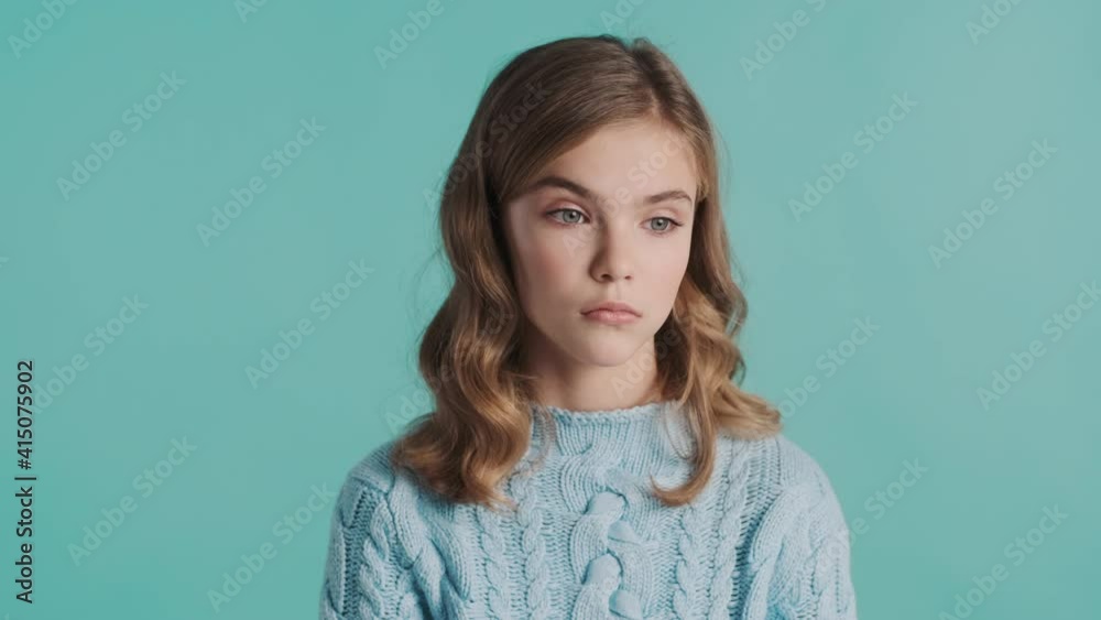 Portrait of blond teenage girl looking bored waving no on camera over colorful background. Tired expression