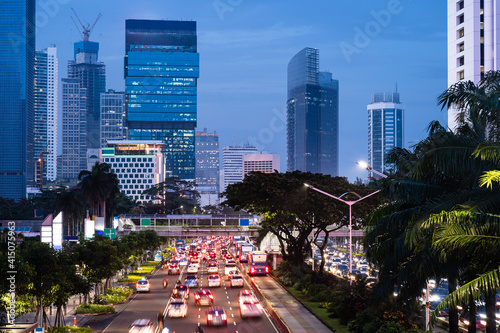 Traffic captured with blurred motion rushes along the famous Sudirman avenue in the heart of Jakarta business district at sunset in Indonesia capital city. photo