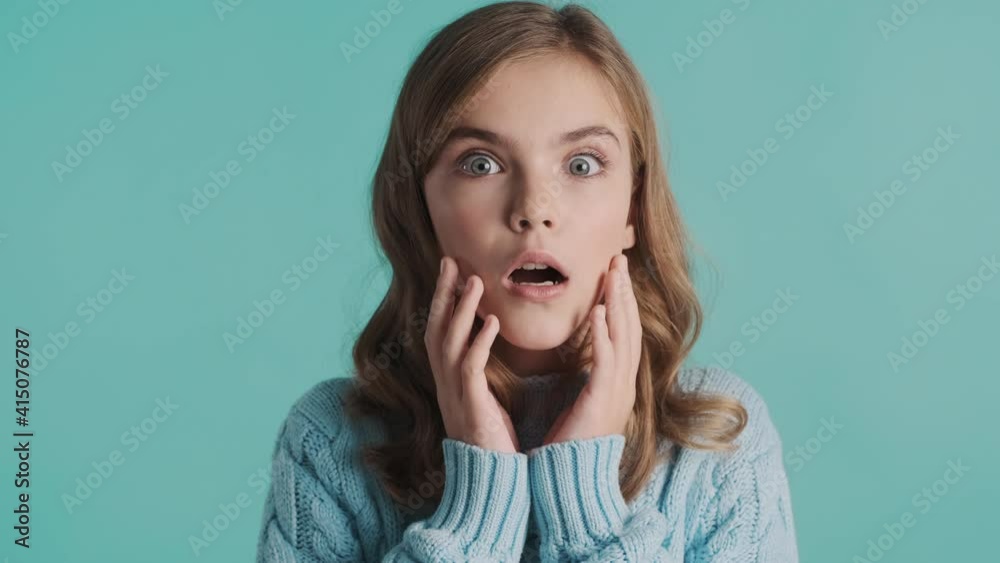 Attractive blond teenager girl looking surprised over blue background. Wow face expression. I can not belive emotion