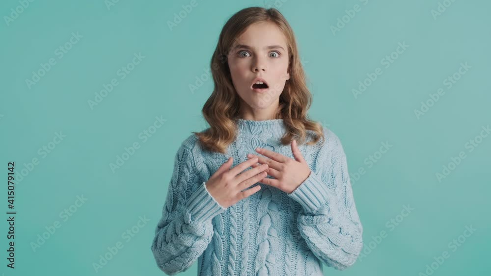 Amazed blond teenager girl looking astonished over blue background. Wow face expression