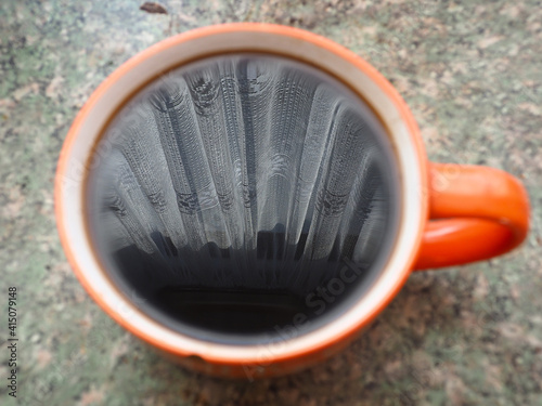 Mug of morning coffee. Spring morning. Light curtains are reflected in the coffee mug. Sunlight comes in through the curtains. photo