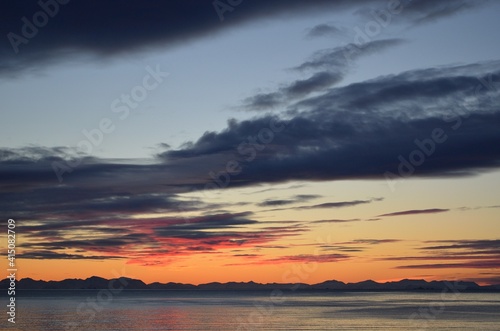 majestic colorful sunset over fjord and mountain landscape with sea fog on the island of Senja, Northern Norway