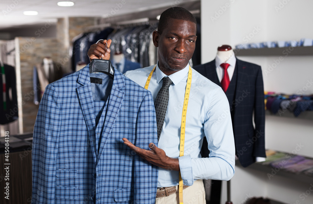 Male tailor demonstrating of fashionable suit in apparel shop. High quality photo