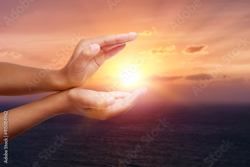Hands of religious little child at sunrise