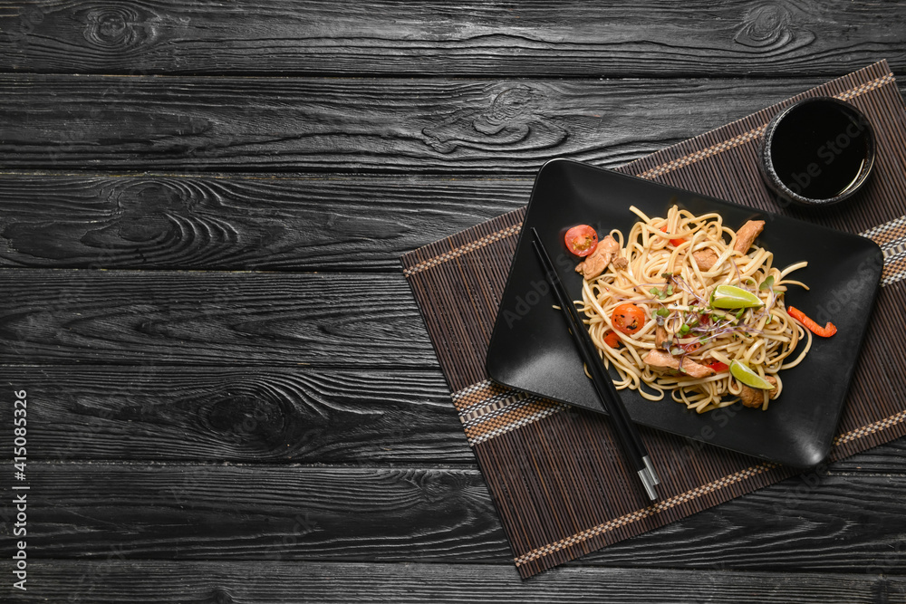 Plate with tasty noodles and meat on dark wooden background