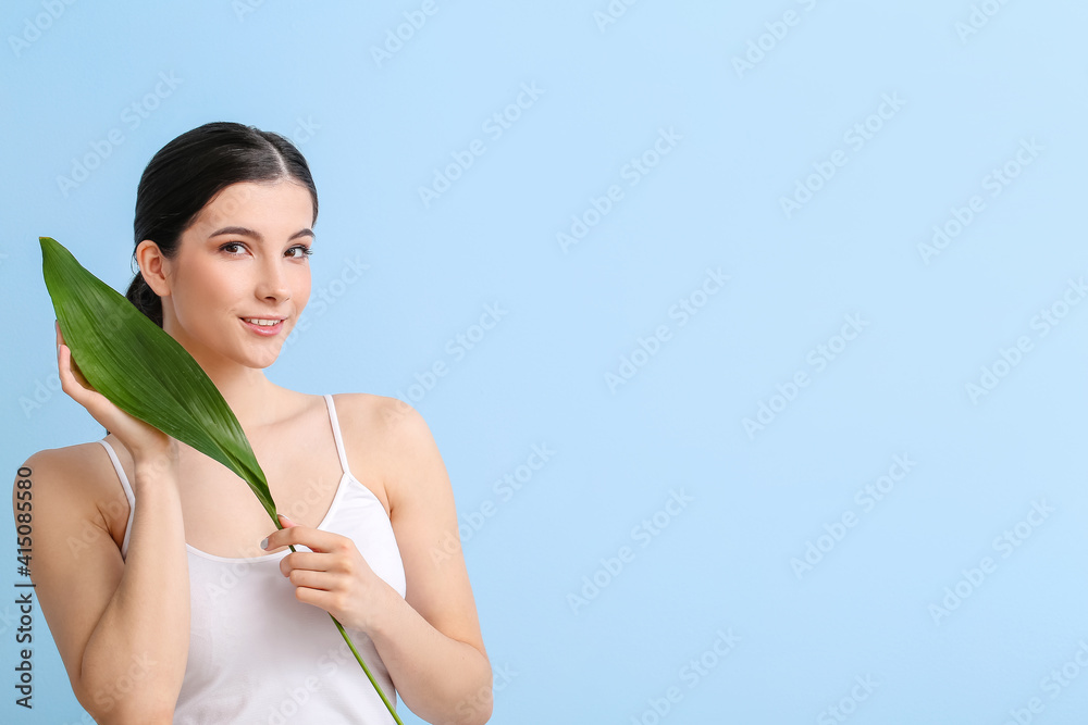 Beautiful young woman with tropical leaf on color background Beautiful young woman with tropical leaf on color background