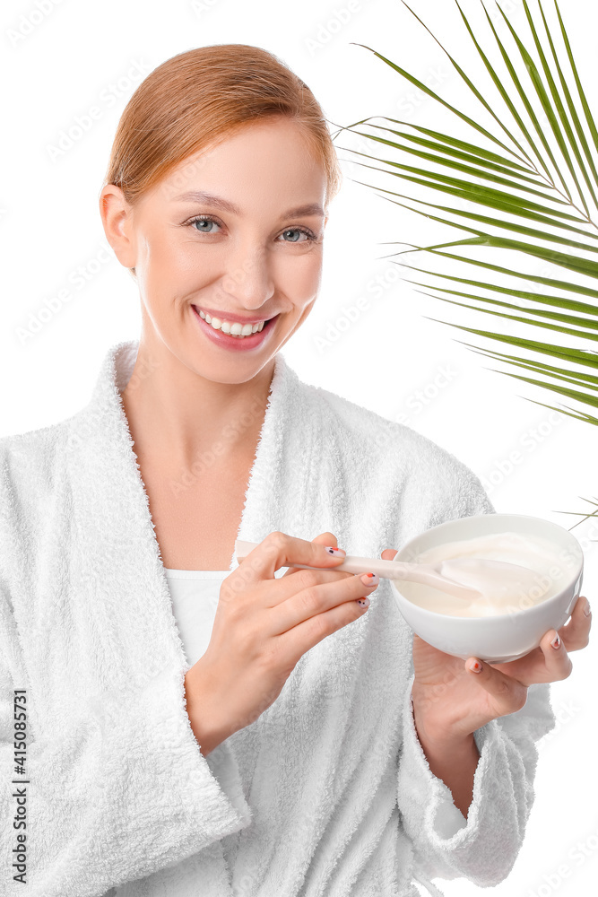 Beautiful young woman with bowl of facial cream and tropical leaf on white background Beautiful young woman with bowl of facial cream and tropical leaf on white background