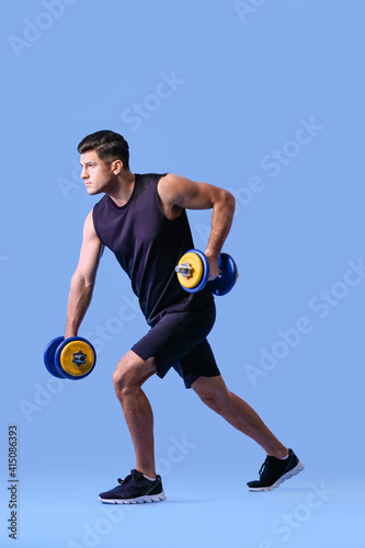 Fototapeta Naklejka Na Ścianę i Meble -  Sporty young man training with dumbbells on color background