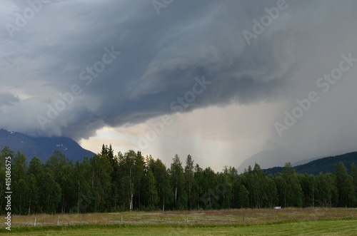 summer thunder storm clouds brewing over forest and mountain landscape