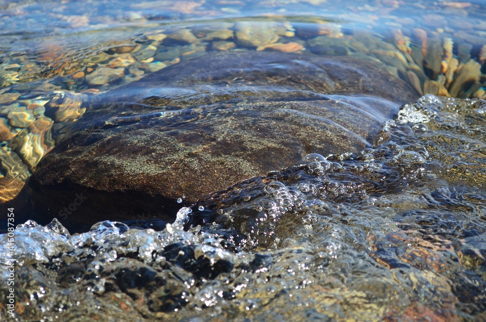 beautiful ripples on river flow over colorful stones in summer sunshine beautiful ripples on river flow over colorful stones in summer sunshine