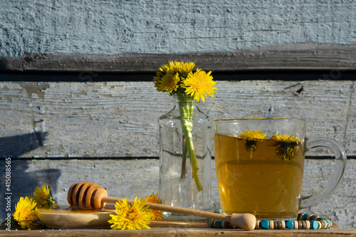 Medicinal Tea from dandelion in  glass cup with honey dandelion against a blue rustic wooden wall photo