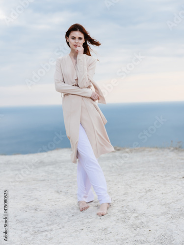 beautiful woman in sweater pants are walking in nature and the ocean in the background