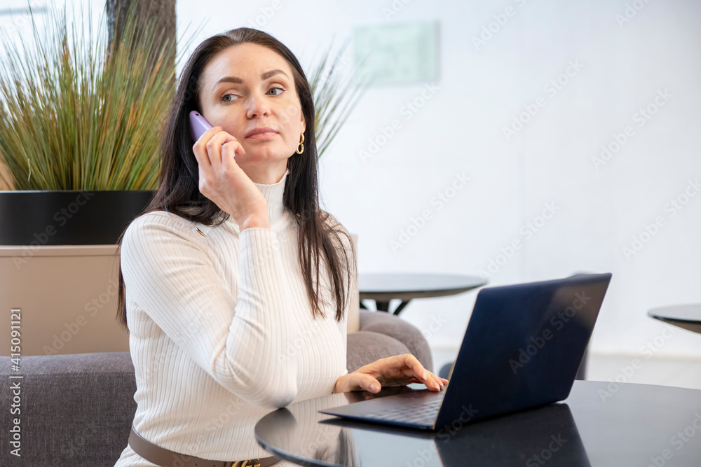 young woman works on laptop and smartphone in cafe. young woman works on laptop and smartphone in cafe.