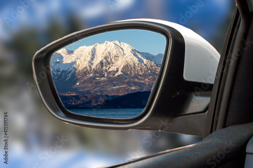 snowy mountain landscape reflected in the rearview mirror of the passenger car.