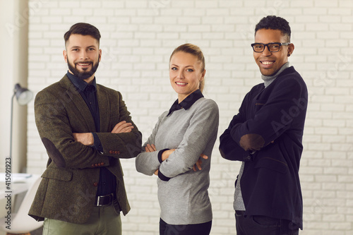 Multiethnic mixed race group of smiling business partners coworkers standing with ahnds crossed and looking at camera in office. International business team, cooperation, multi ethnic group concept photo