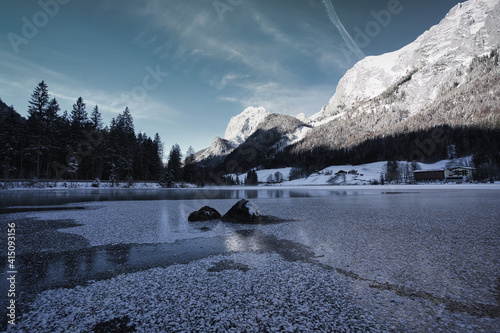 landscape with lake and scnow covered mountains; reflection in partial frozen lake photo