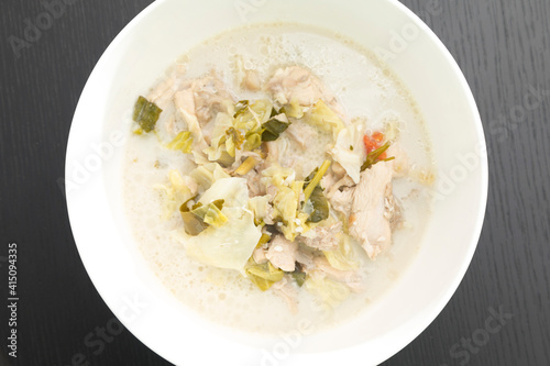Tom Kha Gai or Thai Coconut Chicken Soup in white bowl isolated on black backdrop.