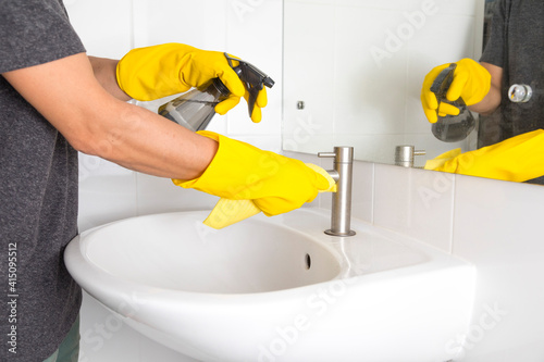 Fototapeta Naklejka Na Ścianę i Meble -  Yellow gloves cleaning sink in the bathroom. Disinfecting the bathroom. Prevention of coronavirus infection.