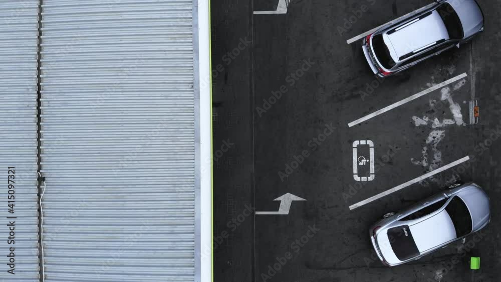 Aerial top view from drone places for disabled people on parking lot of the business center, shopping mall (supermarket) with cars and empty parking spots at day.4k footage