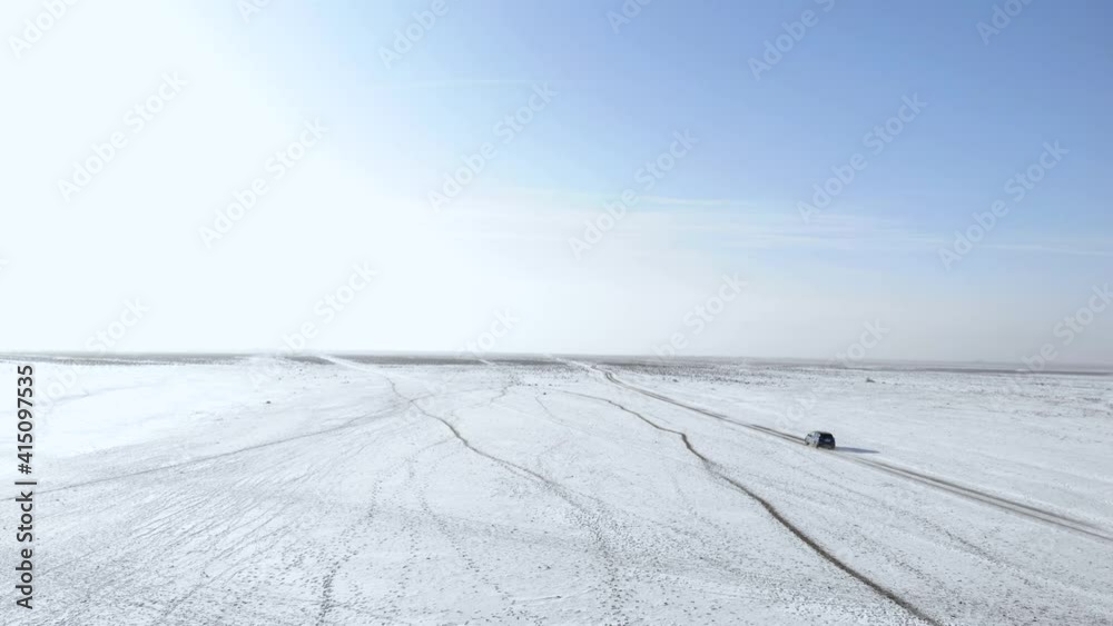 DRONE UPPER DOWN: The car drives through the icy lake. Flying over a car driving on an icy road as a blizzard covers the landscape with deep snow. driving on ice DRONE UPPER DOWN: The car drives through the icy lake. Flying over a car driving on an icy road as a blizzard covers the landscape with deep snow. driving on ice