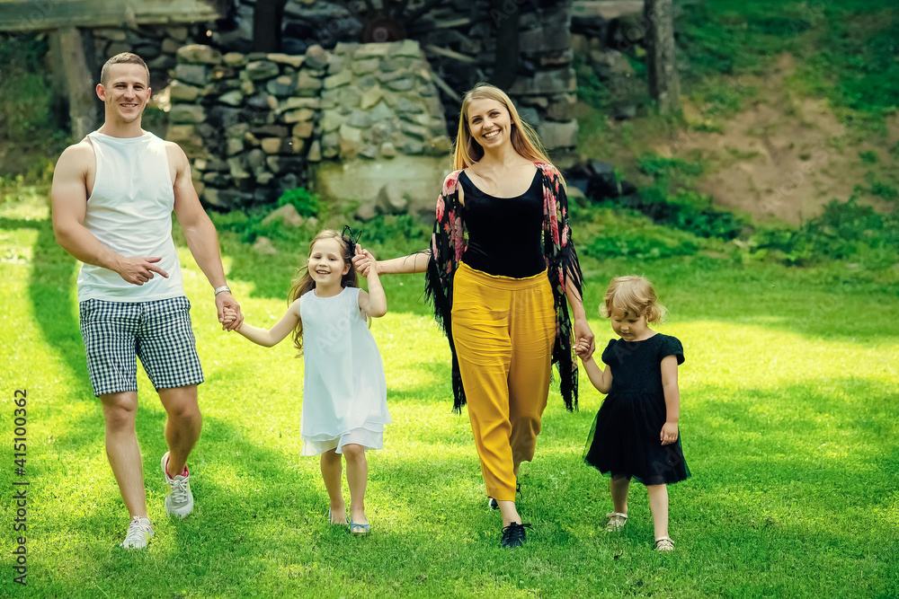 Happy family on summer landscape. Freedom, activity, lifestyle, energy concept. Childhood. Mothers and fathers day. Children and parents walk on green grass.