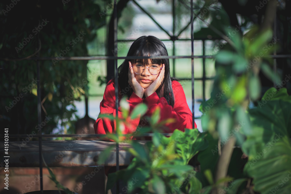 asian teenager wearing red sweater  sitting  outdoor