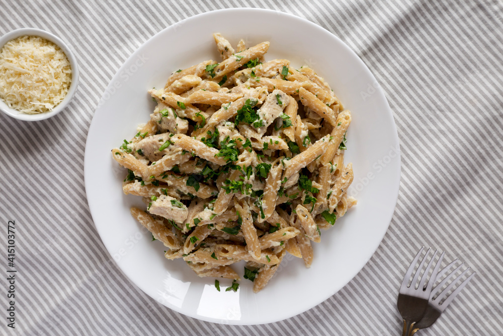 Homemade Chicken Alfredo Penne with Parsley on a white plate, top view. Overhead, from above, flat lay. Homemade Chicken Alfredo Penne with Parsley on a white plate, top view. Overhead, from above, flat lay.