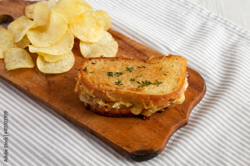 Homemade French Onion Melt Cheese Sandwich with Chips on a rustic wooden board, side view.
