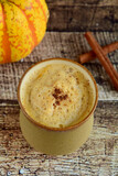 Pumpkin spice latte in a glass with cinnamon. Wooden background