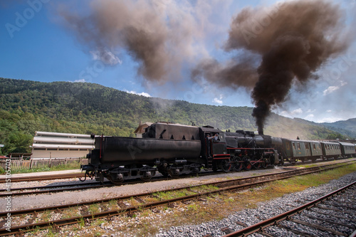 Old steam train leaving the railway station of Tolmin  Slovenia stone bridge