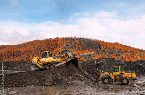 Wheel loaders and bulldozers in operation in an industrial mountainous area