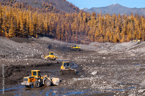 Wheel loaders and bulldozers in operation in an industrial mountainous area