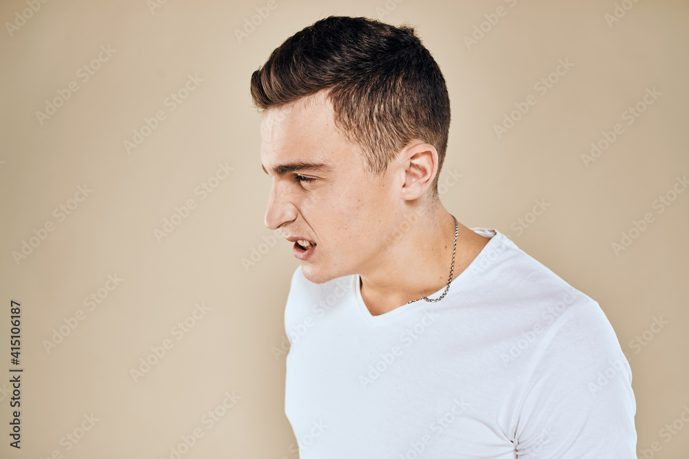 Emotional man white t-shirt gestures with hands lifestyle beige background Emotional man white t-shirt gestures with hands lifestyle beige background