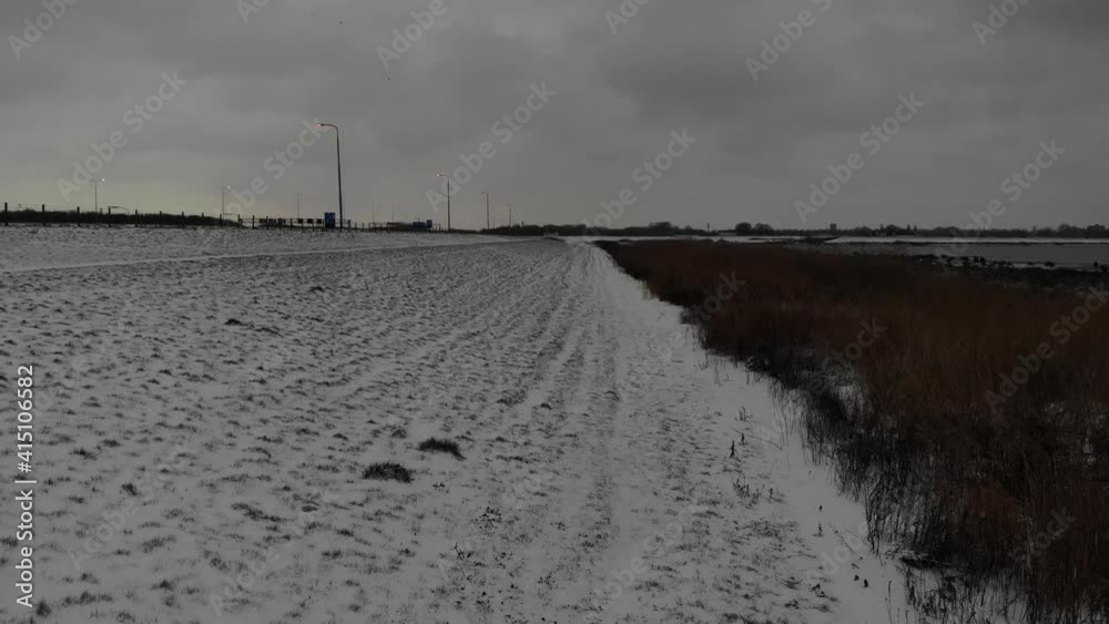 Field Covered With Snow With Brown Reeds On The Side In Winter. wide shot