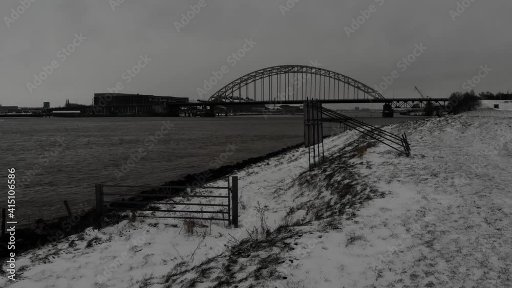 Snowy Riverside Of Noord With A Bridge On The Background In Netherlands. - aerial, black and white Snowy Riverside Of Noord With A Bridge On The Background In Netherlands. - aerial, black and white