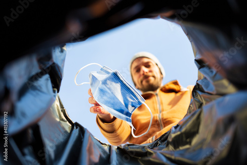 Point of view shot of man throwing away surgical mask in trash can