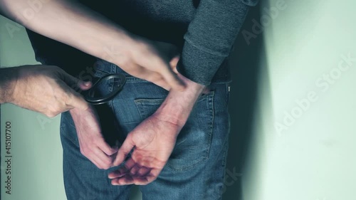 arrest of a criminal. Arrest of the offender without resistance. Policeman puts the handcuffs on the hands of criminal, hands closeup. Detention of the accused business person.