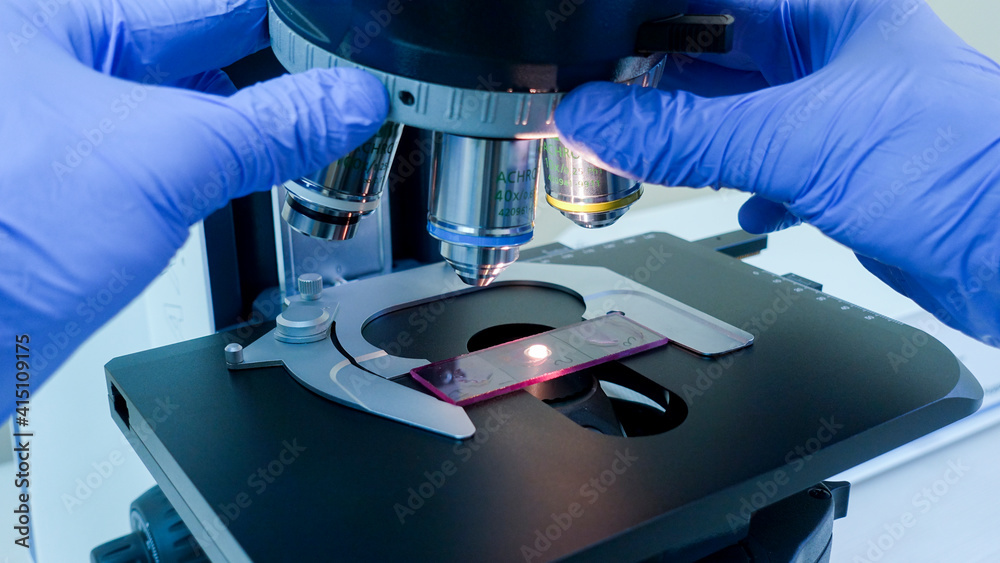 The scientist changes the magnification with two hands on the