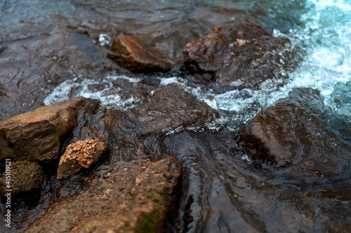 Stones in the rough river water. Stones under water. View from above. Winter fast river.