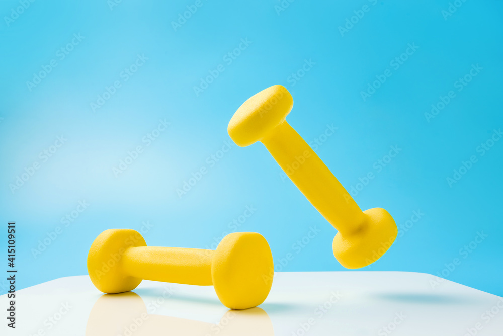 Yellow dumbbells against a blue and white background. Yellow dumbbells against a blue and white background.