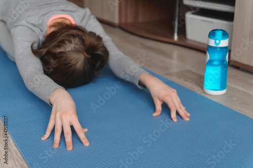 Teenage girl doing fitness exercise, practicing yoga at home. Healthy lifestyle concept. Workout at home. Home interior, natural light. Selective focus