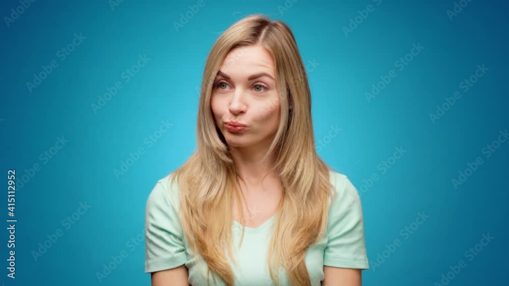 Thoughtful woman looking aside with pensive expression againast blue background Thoughtful woman looking aside with pensive expression againast blue background
