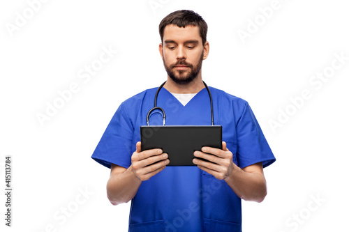 medicine, healthcare and technology concept - doctor or male nurse in blue uniform with stethoscope using tablet pc computer over white background