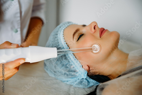 Receiving electric d'arsonval facial massage procedure at beauty salon photo